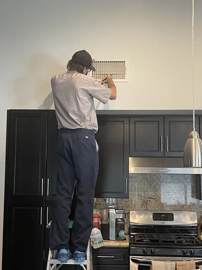 Technician inspecting an air vent during HVAC service in Euclid